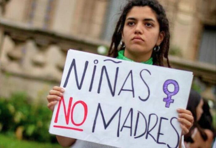 Mujer con cartel sobre la prevención del embarazo en la adolescencia