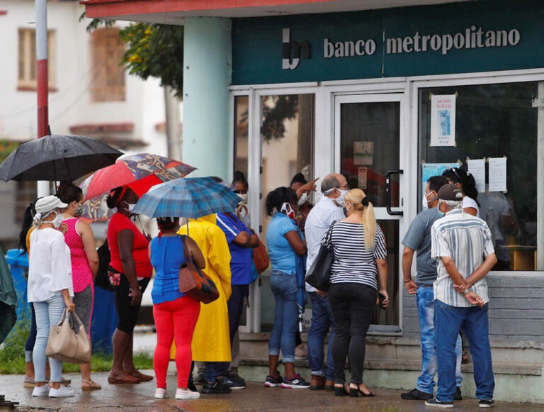 Personas hacen fila frente a un banco en Cuba.