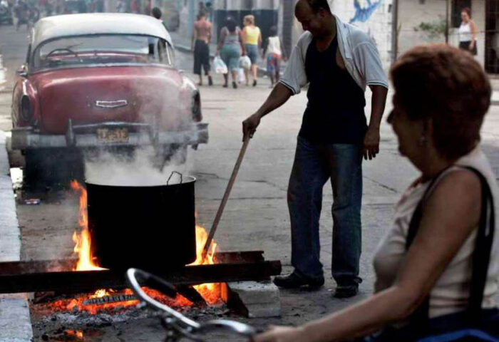 Personas cocinando con leña en una calle de La Habana.