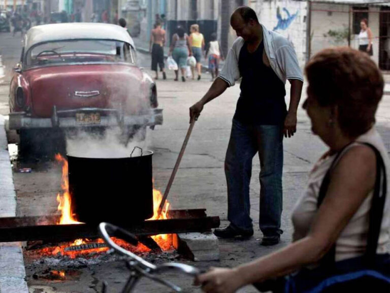 Personas cocinando con leña en una calle de La Habana.